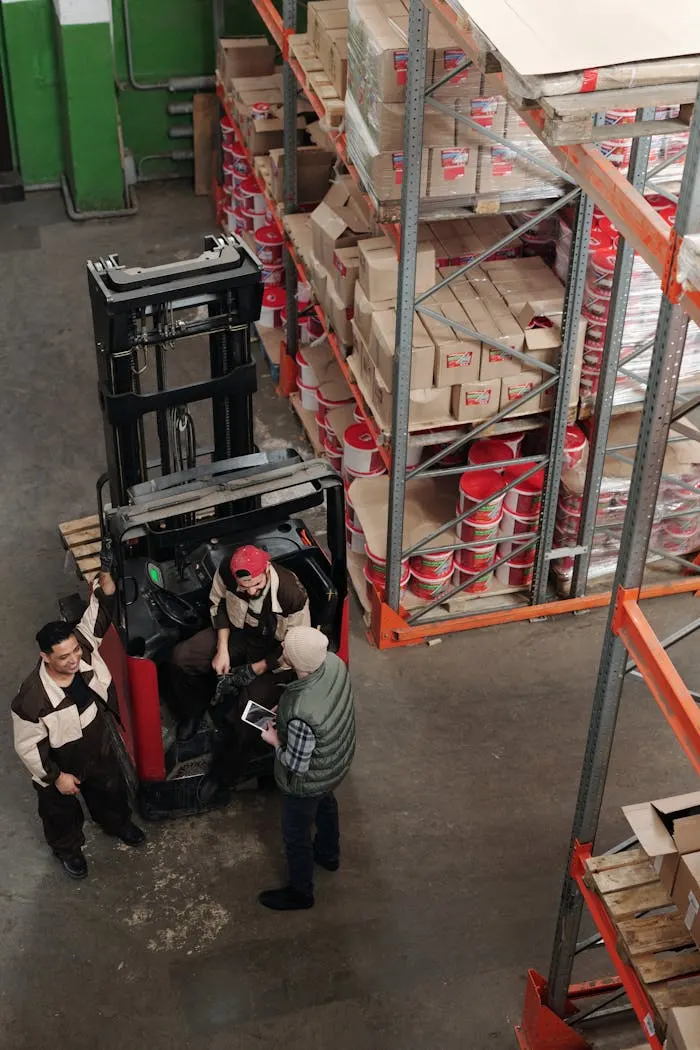 Warehouse team reviewing stock data on a tablet beside a forklift