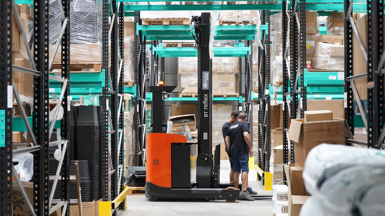 Mastering the First Impression: Your intriguing post title goes here Warehouse scene featuring workers and a forklift navigating aisles for logistics and inventory management.